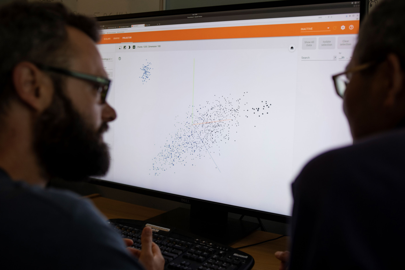 Data & AI scientists in discussion over a monitor showing a graphical representation of data